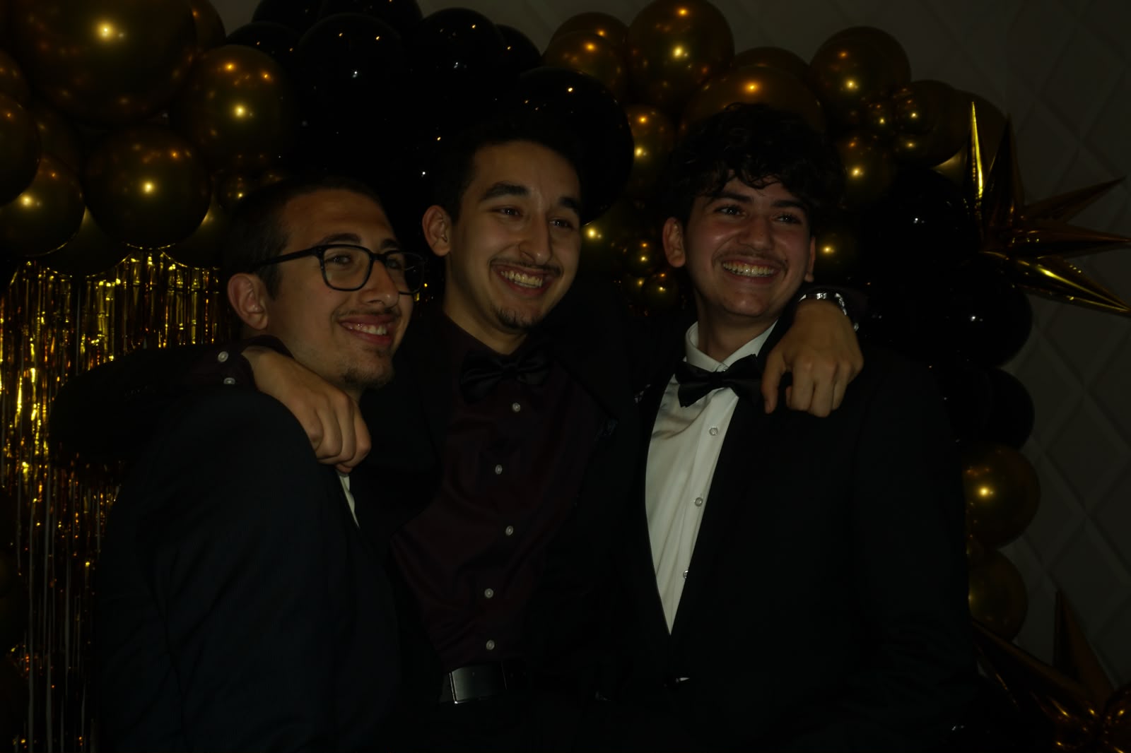Three guests at a black-and-gold gala